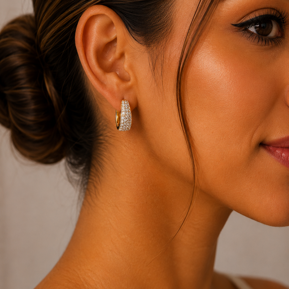 Aretes tipo huggie en chapa de oro con frente de zirconias pavé brillantes y diseño elegante de 2 cm.