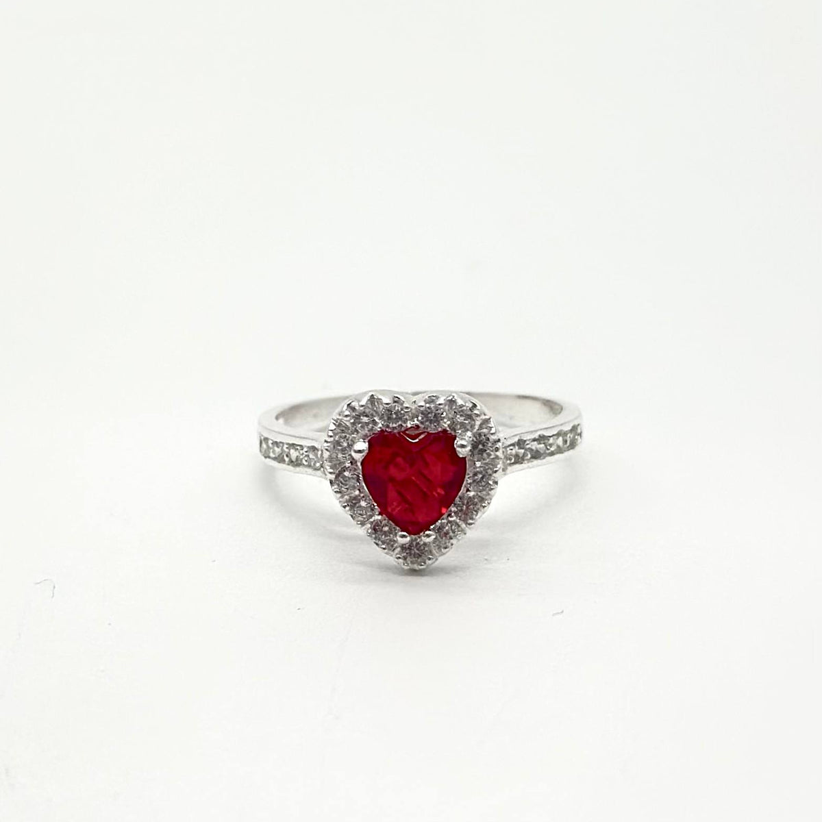 Anillo de plata 925 con piedra roja en forma de corazón rodeada de zirconias brillantes y acabado pulido.