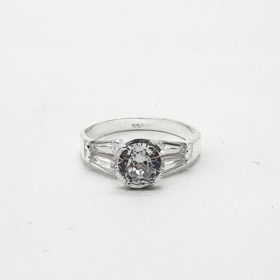 Anillo de plata 925 con zirconia central redonda y detalles laterales de corte baguette brillantes.
