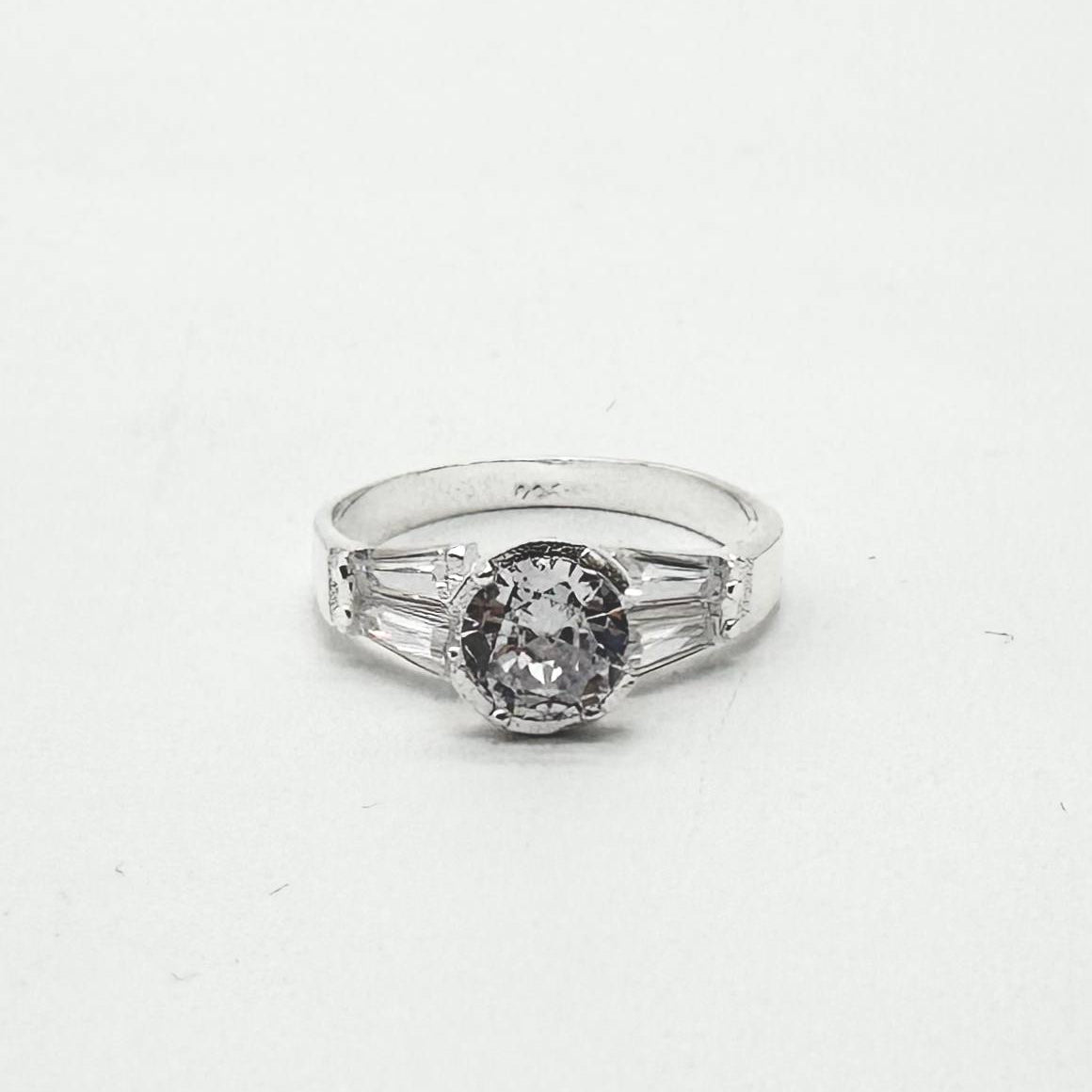 Anillo de plata 925 con zirconia central redonda y detalles laterales de corte baguette brillantes.