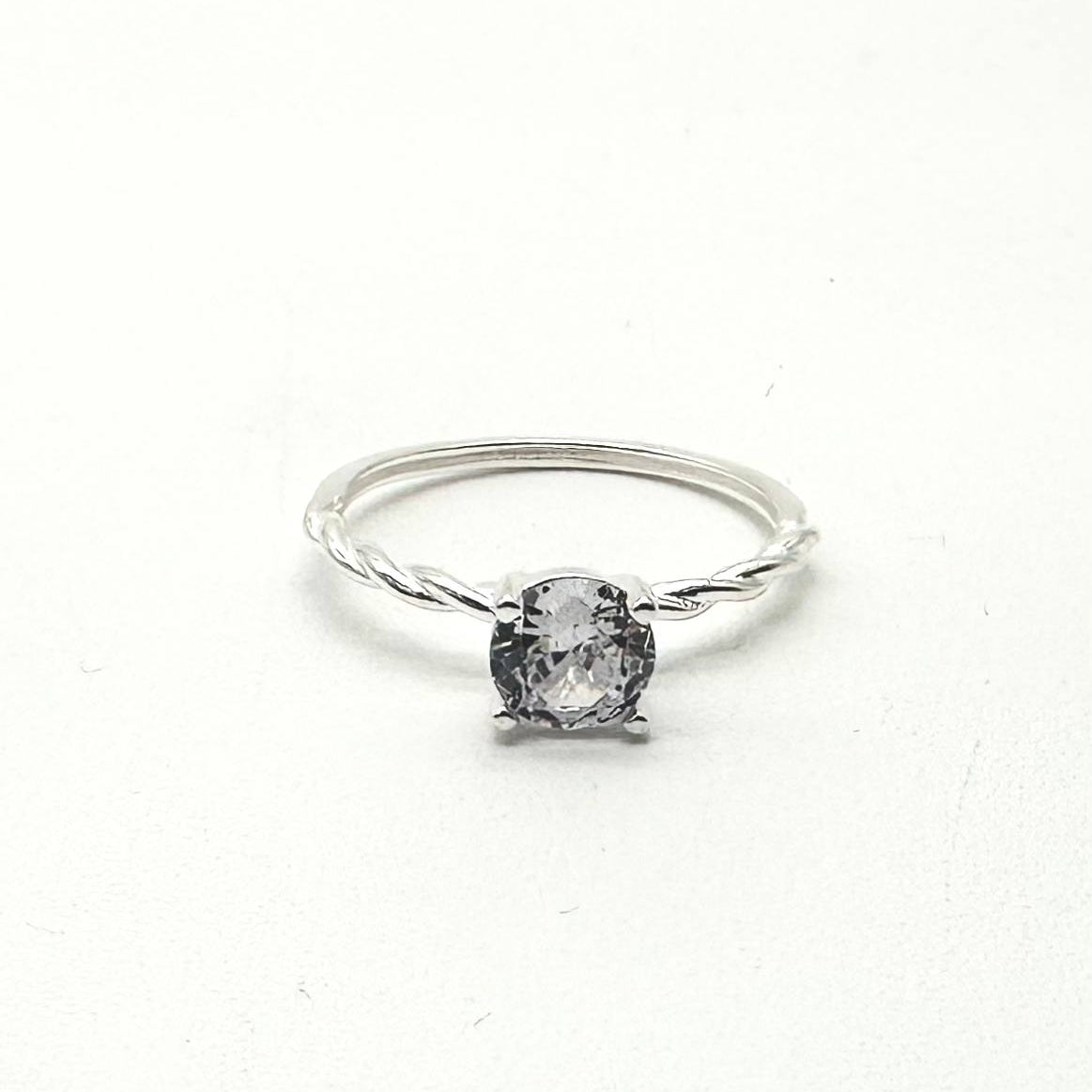 Anillo solitario de plata 925 con zirconia redonda brillante y aro con diseño trenzado.